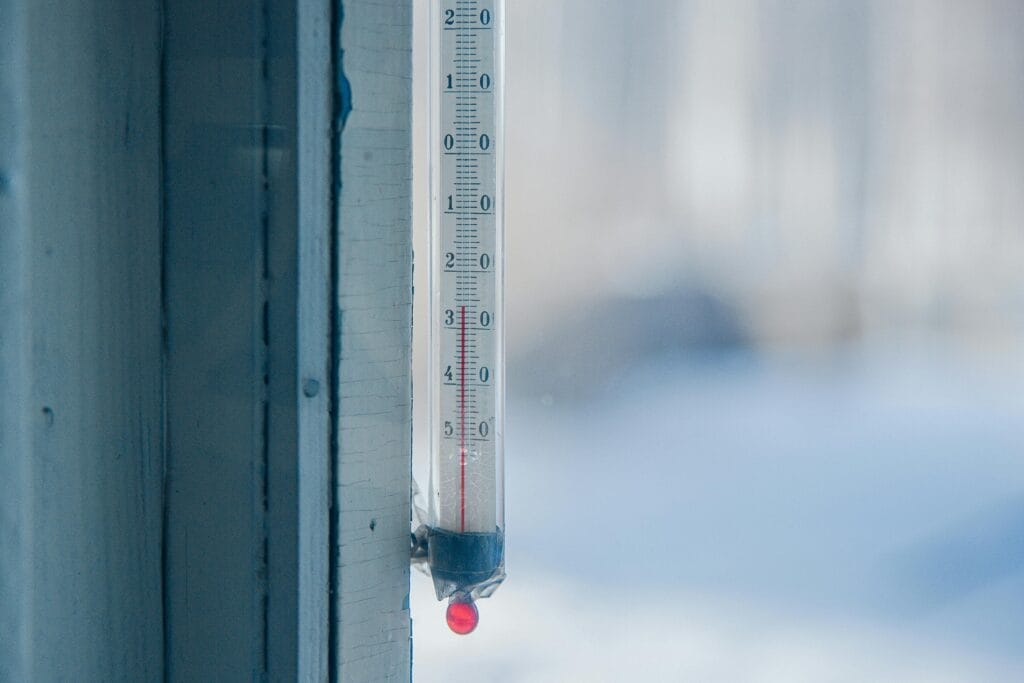 Close-up of an outdoor thermometer against a frosty winter backdrop.